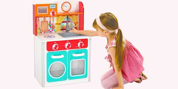A girl playing with Chad Valley wooden junior kitchen.